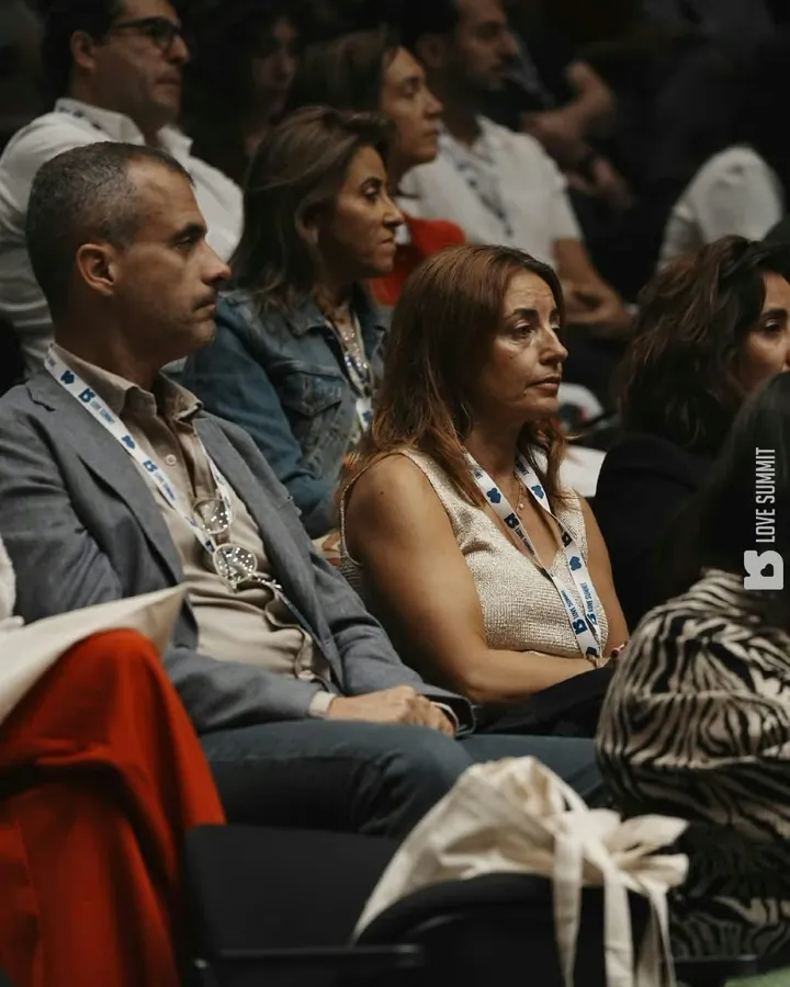 A Ana sentada na plateia do Love Summit, a ouvir uma palestra