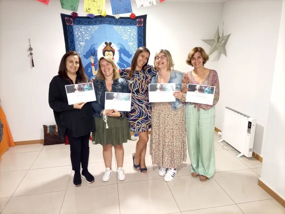 Cinco participantes de uma formação, de pé, com os certificados na mão