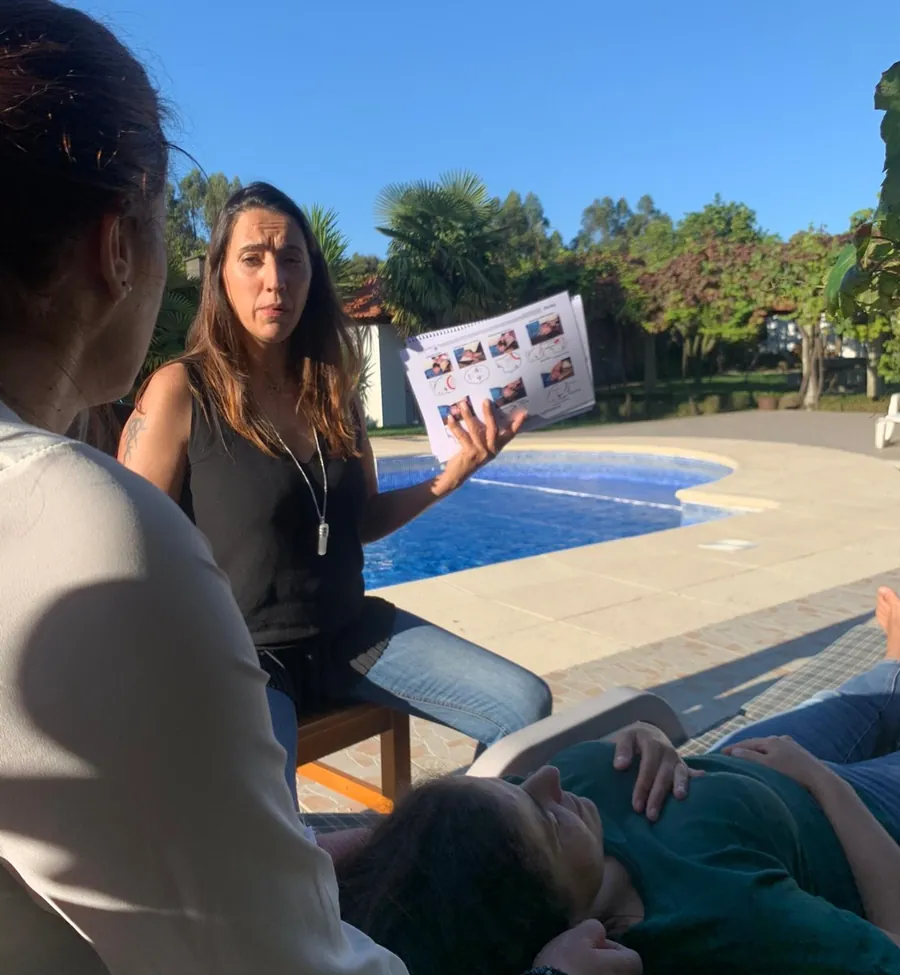A Ana a explicar com uma folha na mão, num workshop ao ar livre junto a uma piscina