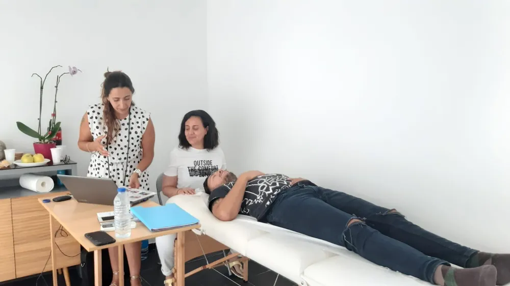 Prática numa formação de Barras de Access®: um participante deitado na marquesa e duas pessoas a trabalhar